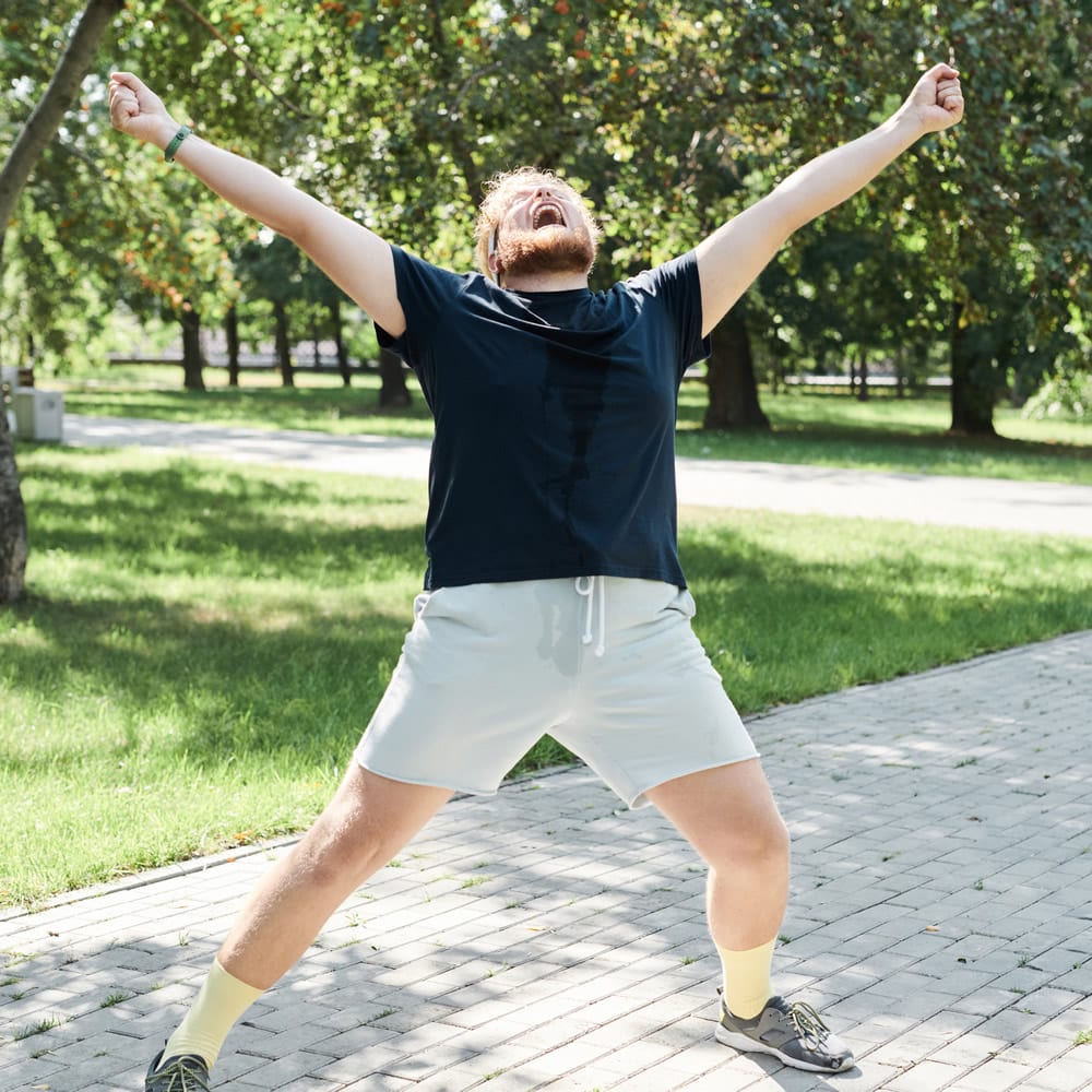 Man raising arms in park Man raising arms in park after training