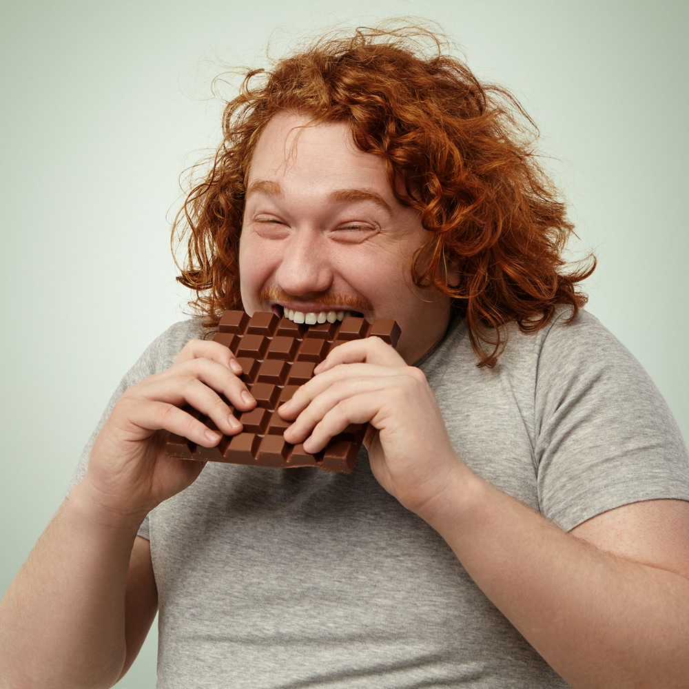 Overweight man eating chocolate Overweight man eating chocolate