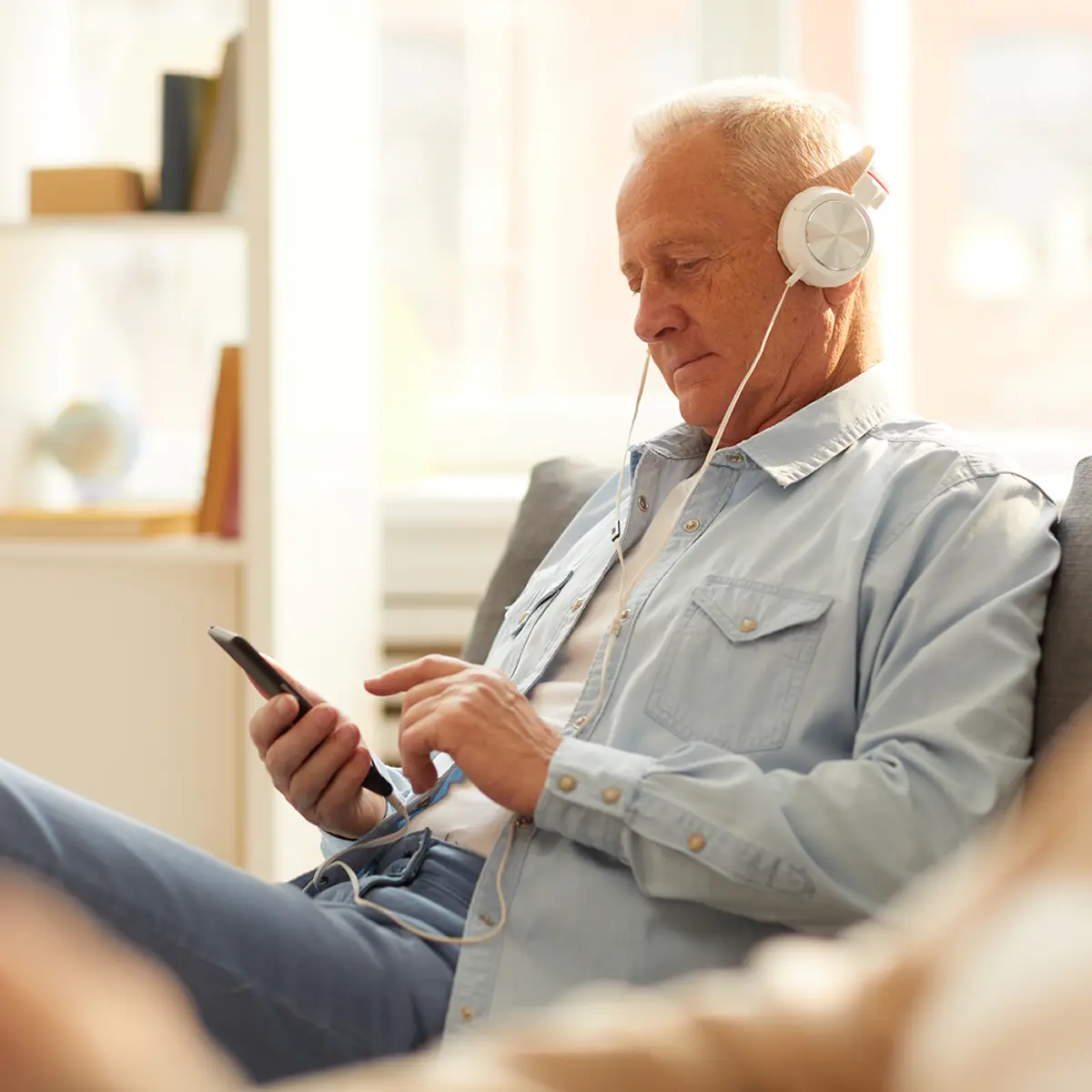 Senior man enjoying On Demand Hypnosis on mobile phone with headphones
