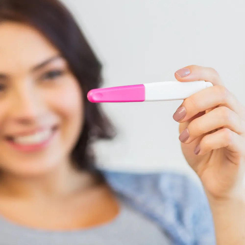Smiling hypnofertility client holding pregnancy test Smiling hypnofertility client holding pregnancy test in Sydney home