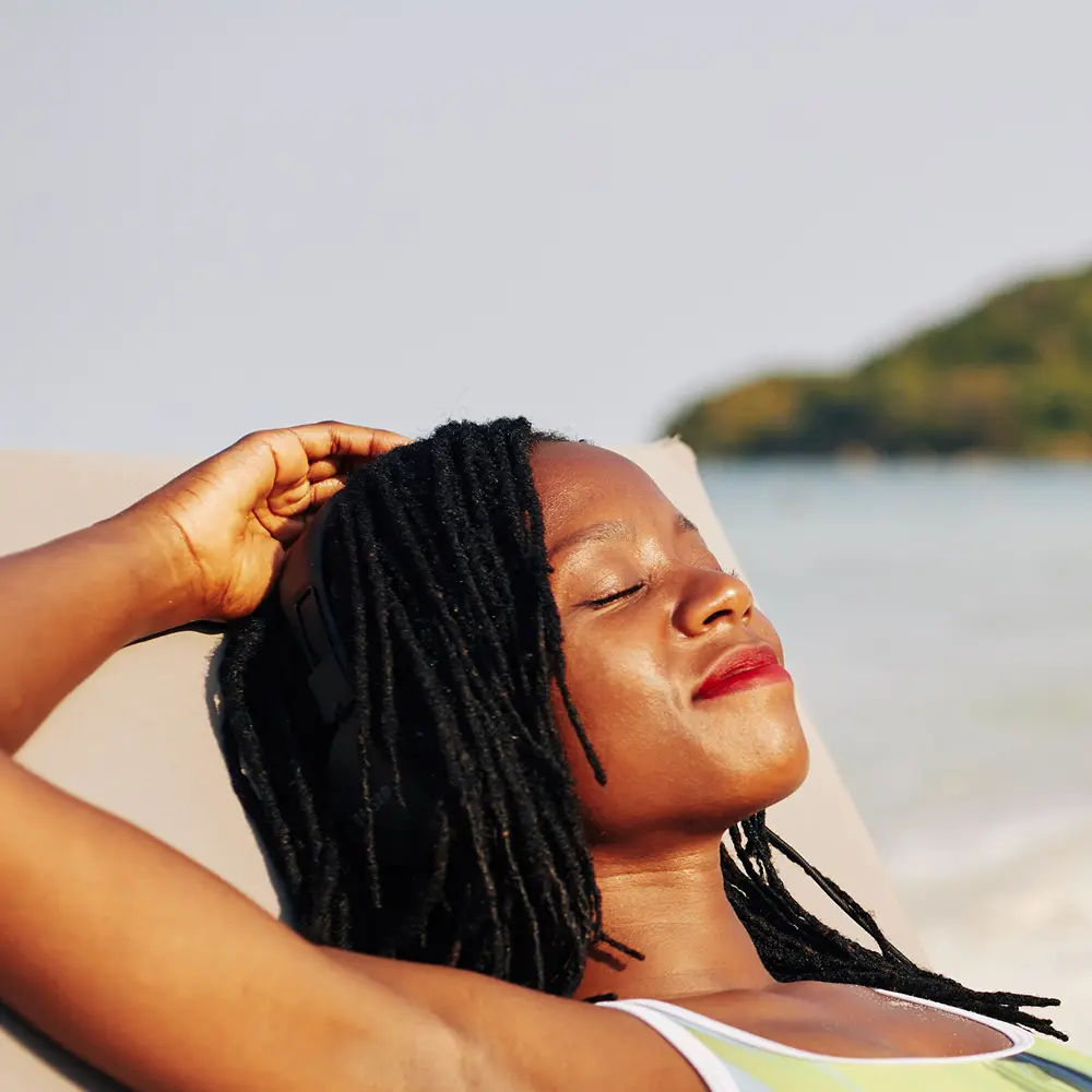 Woman relaxing at Sydney beach after hypnotherapy for bad habits